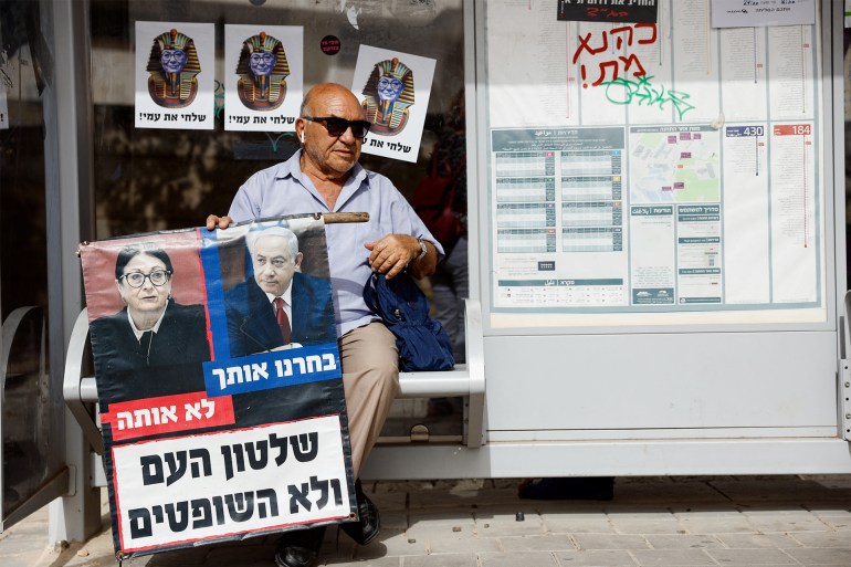 A protester in support of a judicial overhaul holds a sign depicting President of the Supreme Court of Israel Esther Hayut and Israeli Prime Minister Netanyahu with the words, "We chose you, not her. Rule of the people, not the judges" on the day that Israel's Supreme Court is set to discuss petitions against new legislation that Prime Minister Benjamin Netanyahu's religious-nationalist coalition passed as part of a plan to overhaul the judiciary, outside Israel's Supreme Court in Jerusalem September 12, 2023. REUTERS/Amir Cohen