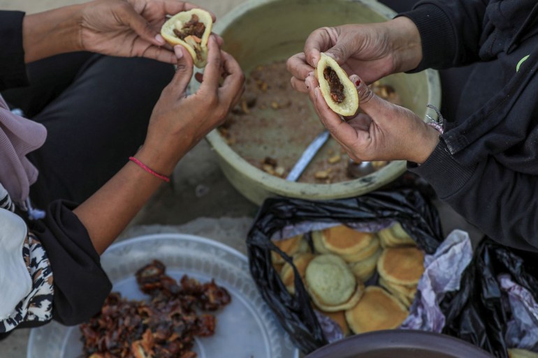 Siham and her sister stuff some qatayef with a sweet crushed nut mixture, ready to be fried and soaked in syrup for dessert [Abdelhakim Abu Riash/Al Jazeera]